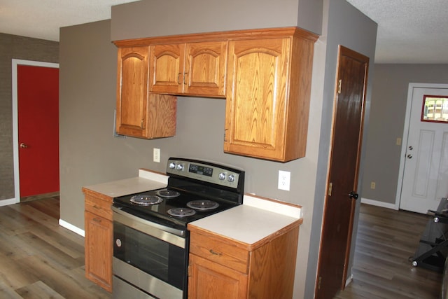 kitchen with dark wood-style floors, electric range, light countertops, and baseboards