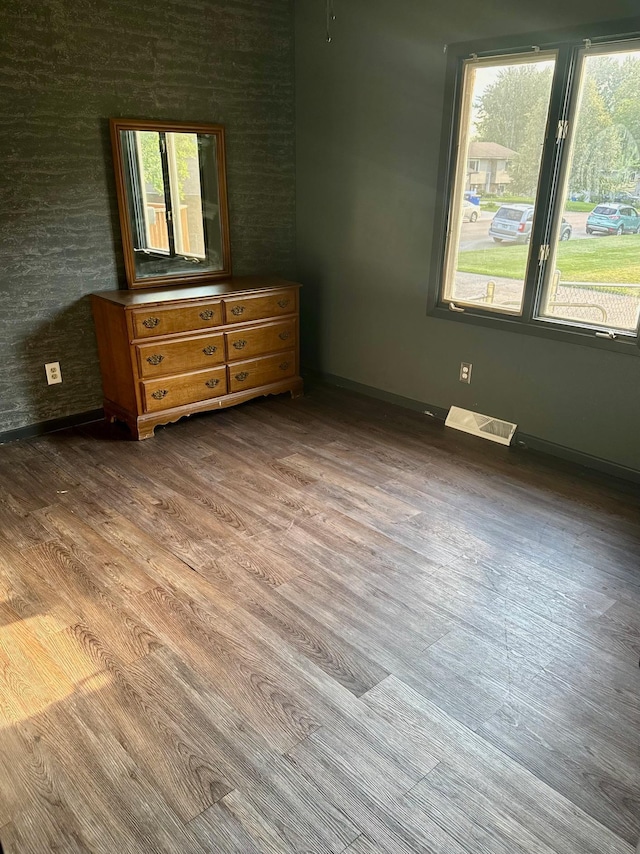 unfurnished bedroom with wood finished floors, visible vents, and baseboards