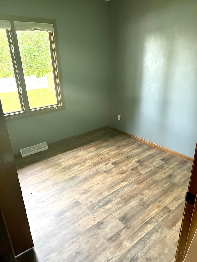 unfurnished room with visible vents, baseboards, and wood finished floors