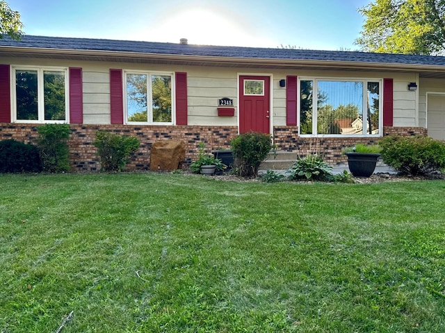 single story home with brick siding, an attached garage, and a front lawn