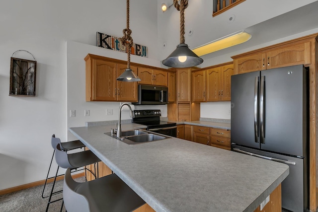 kitchen with a kitchen breakfast bar, brown cabinets, appliances with stainless steel finishes, and a sink