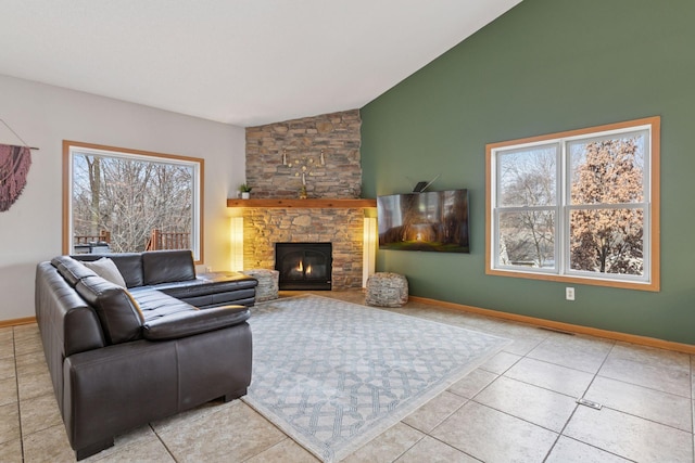 living room featuring a stone fireplace, lofted ceiling, baseboards, and tile patterned floors