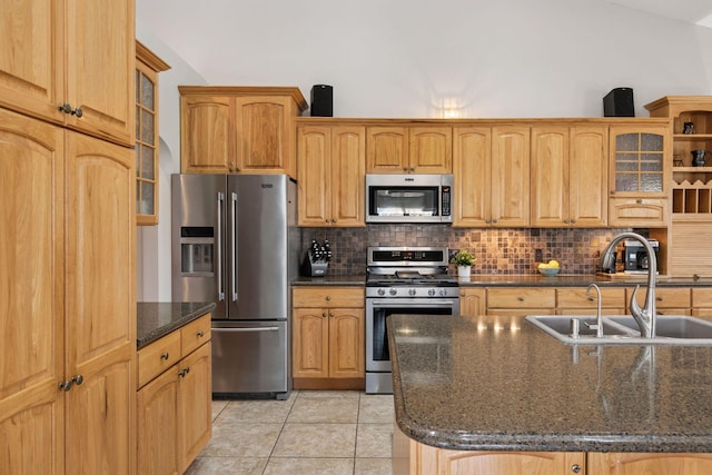 kitchen with light tile patterned flooring, a sink, stainless steel appliances, vaulted ceiling, and tasteful backsplash