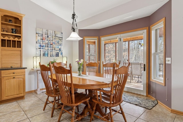 dining room with light tile patterned floors, baseboards, and vaulted ceiling