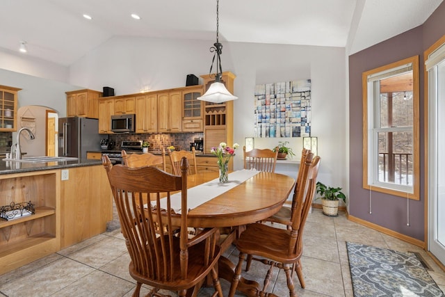 dining area with light tile patterned floors, baseboards, and high vaulted ceiling