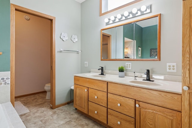 bathroom with a sink, baseboards, toilet, and double vanity