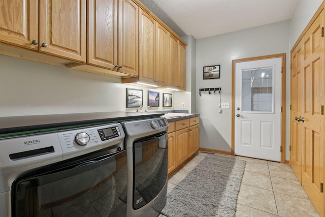 clothes washing area featuring baseboards, washer and clothes dryer, light tile patterned floors, cabinet space, and a textured ceiling