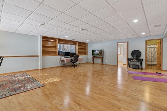 interior space featuring a paneled ceiling, baseboards, and wood finished floors