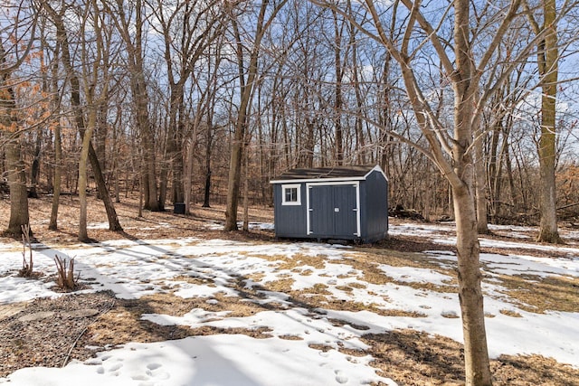 snow covered structure with an outdoor structure and a shed