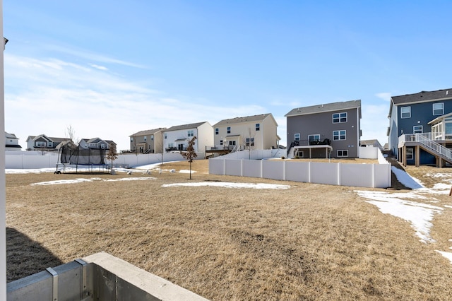 view of yard featuring a residential view, a trampoline, and fence