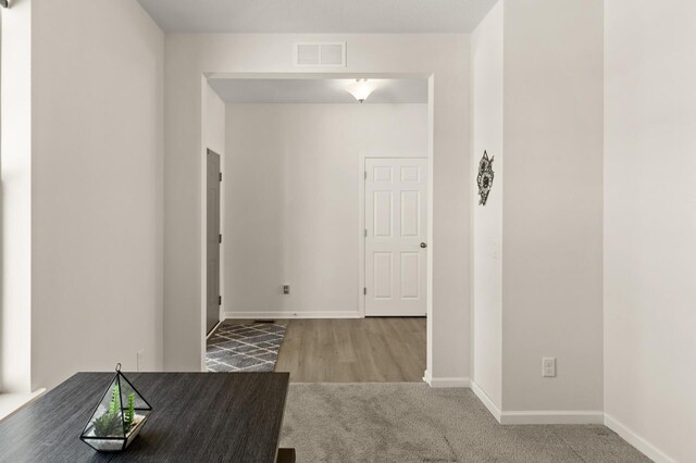 hall featuring baseboards, visible vents, and carpet floors