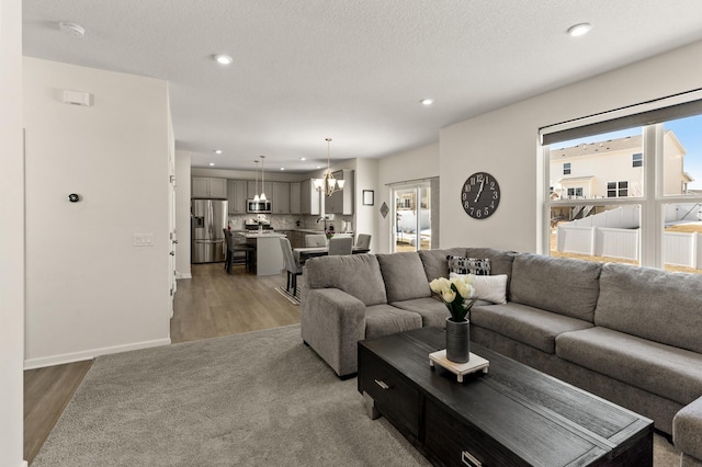 living area with recessed lighting, plenty of natural light, an inviting chandelier, and light wood-style flooring