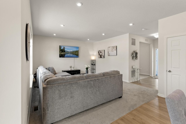 living area with light wood-type flooring, visible vents, baseboards, and recessed lighting