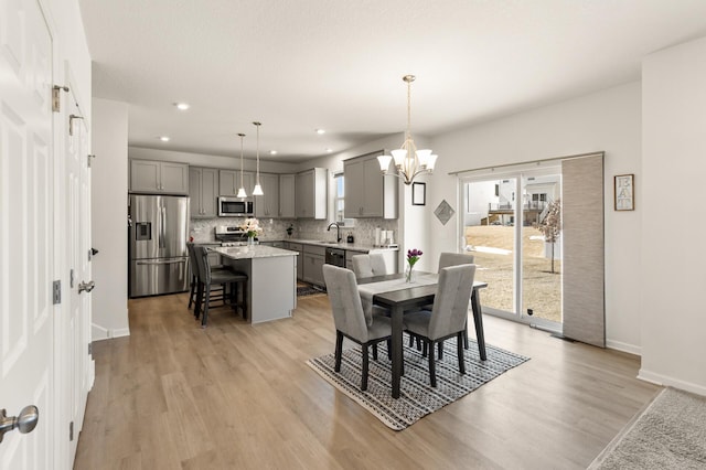 dining room featuring recessed lighting, light wood-style floors, baseboards, and a notable chandelier