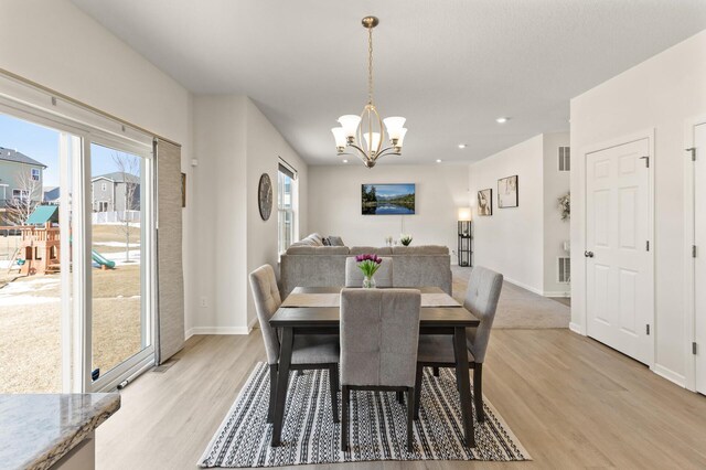 dining area with an inviting chandelier, light wood-style flooring, and a wealth of natural light