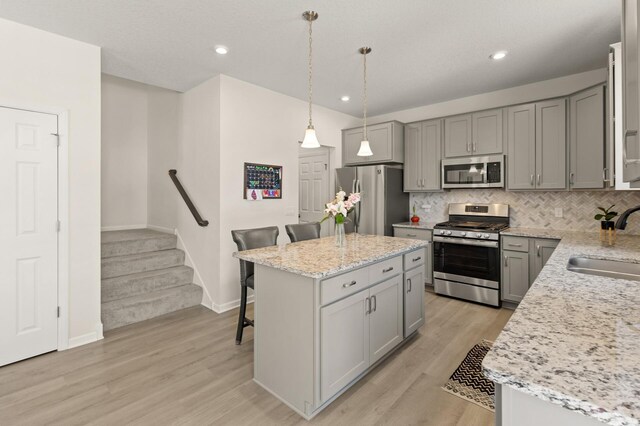 kitchen featuring a sink, gray cabinetry, a breakfast bar, and stainless steel appliances