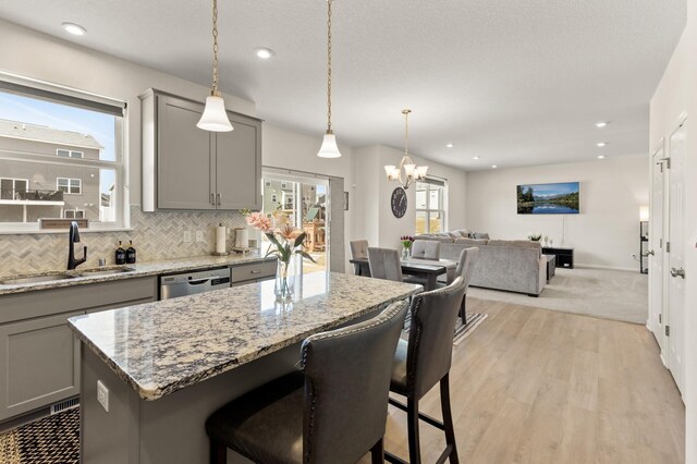 kitchen featuring backsplash, gray cabinets, stainless steel dishwasher, and a sink