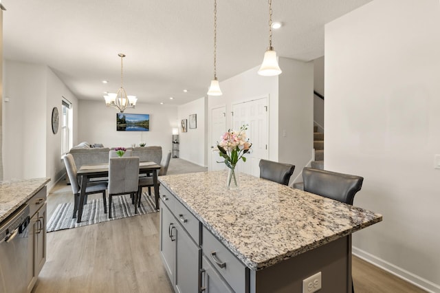 kitchen featuring stainless steel dishwasher, light wood-style floors, gray cabinets, and a kitchen island