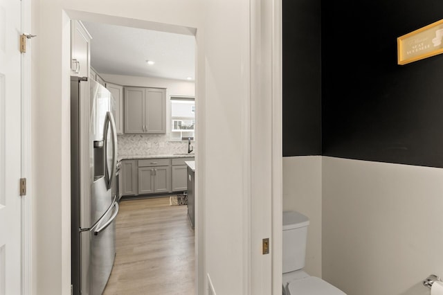 interior space featuring vanity, toilet, wood finished floors, and backsplash