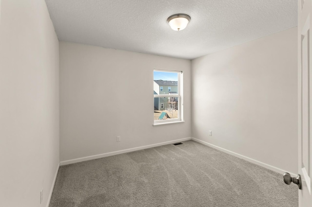 unfurnished room featuring carpet flooring, a textured ceiling, baseboards, and visible vents