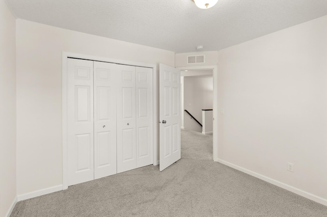 unfurnished bedroom with baseboards, visible vents, carpet floors, and a textured ceiling