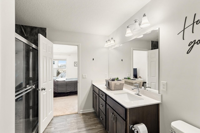 full bathroom featuring connected bathroom, toilet, vanity, wood finished floors, and a textured ceiling