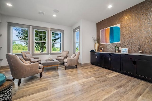 living area with recessed lighting, visible vents, light wood-type flooring, and baseboards