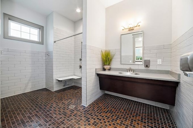 full bath with vanity, a wainscoted wall, a tile shower, tile walls, and tile patterned floors