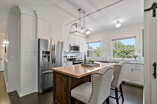 79 Western Ave N Unit 308, Saint Paul, MN 55102 - kitchen featuring appliances with stainless steel finishes, a sink, decorative backsplash, white cabinets, and a kitchen island