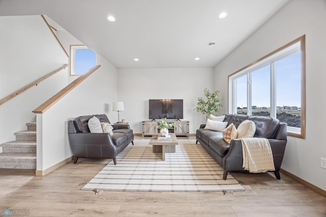 living room with stairs, plenty of natural light, and light wood-type flooring