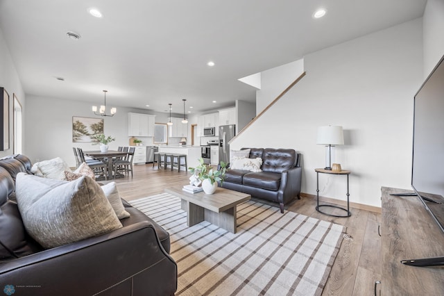 living area featuring recessed lighting, light wood-style flooring, and a notable chandelier