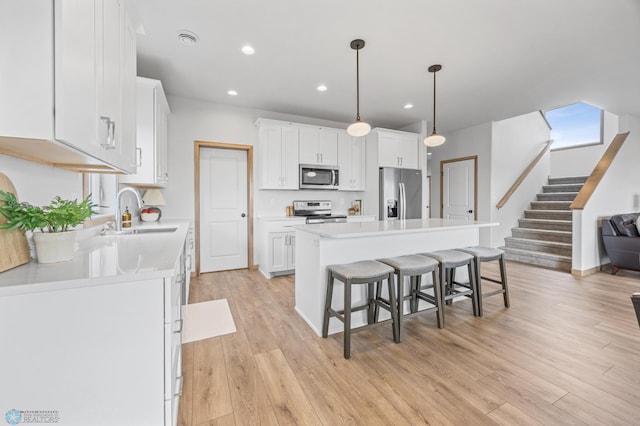 kitchen with a kitchen bar, a center island, white cabinetry, a sink, and appliances with stainless steel finishes
