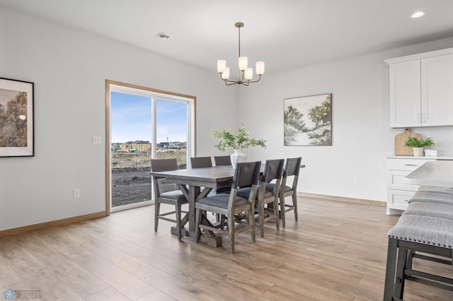 dining space with light wood-style floors, baseboards, and an inviting chandelier