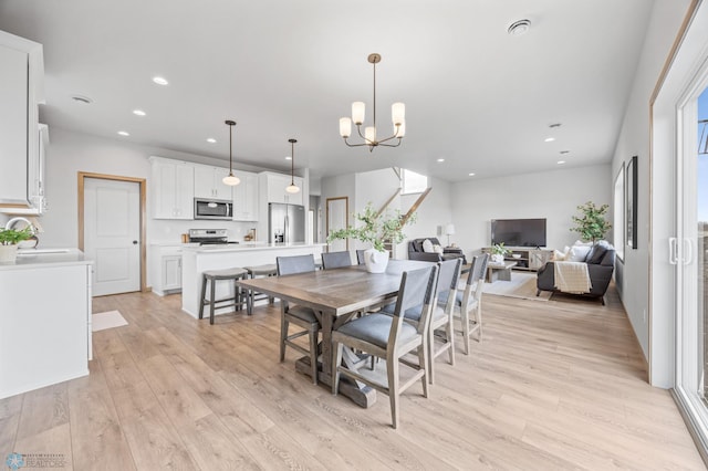 dining room with recessed lighting, light wood finished floors, and an inviting chandelier