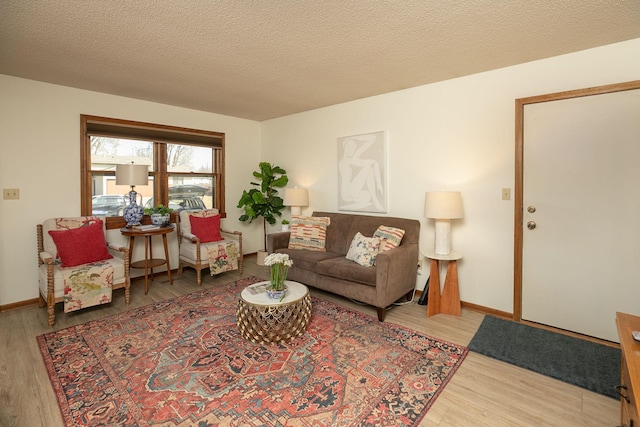 living room with a textured ceiling, baseboards, and wood finished floors