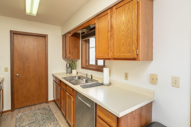 kitchen with a sink, dishwasher, brown cabinetry, and light countertops