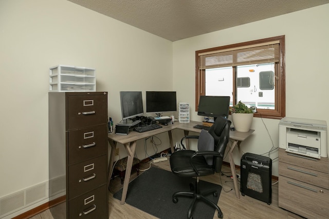 office space with visible vents, a textured ceiling, and light wood-style flooring