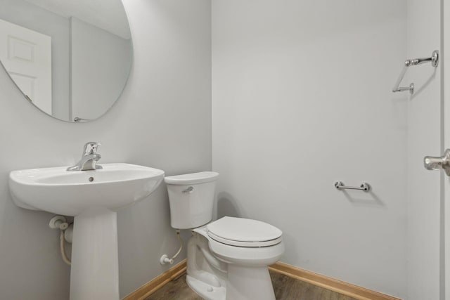 bathroom featuring toilet, wood finished floors, and baseboards