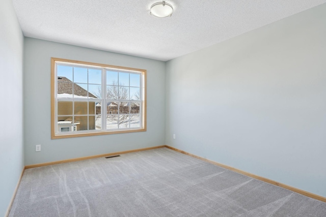 carpeted empty room with visible vents, baseboards, and a textured ceiling