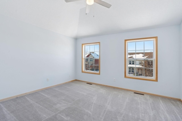 spare room featuring a wealth of natural light, visible vents, carpet flooring, and lofted ceiling