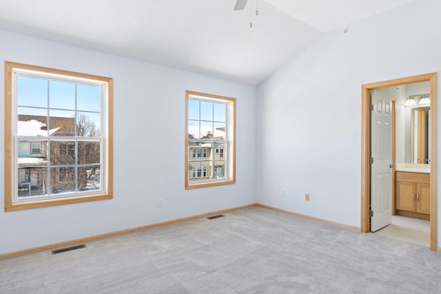 unfurnished room with a wealth of natural light, visible vents, light carpet, and lofted ceiling