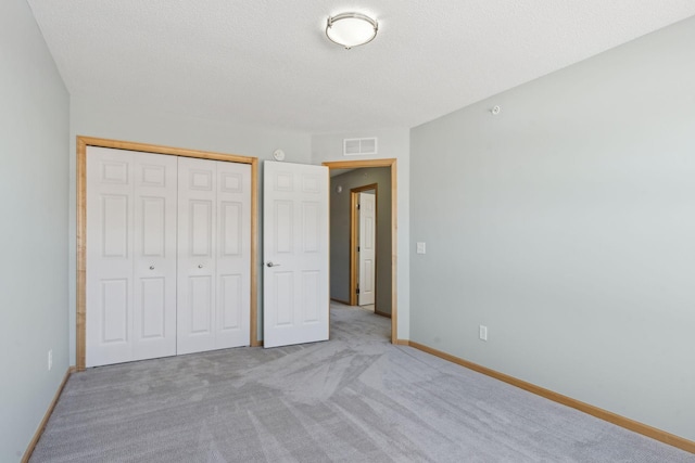 unfurnished bedroom with baseboards, visible vents, a closet, a textured ceiling, and carpet flooring