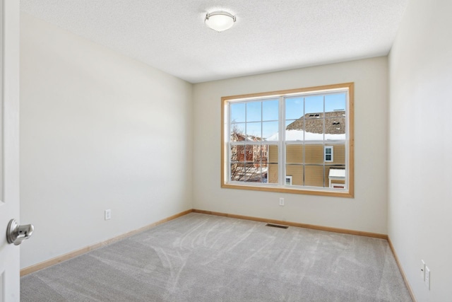 empty room with visible vents, baseboards, carpet, and a textured ceiling