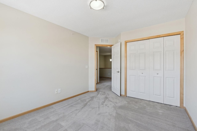 unfurnished bedroom with visible vents, baseboards, carpet, a closet, and a textured ceiling