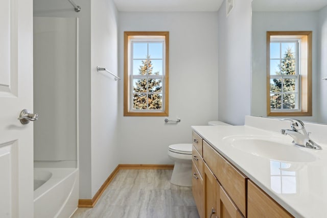 bathroom featuring toilet, plenty of natural light, vanity, and baseboards