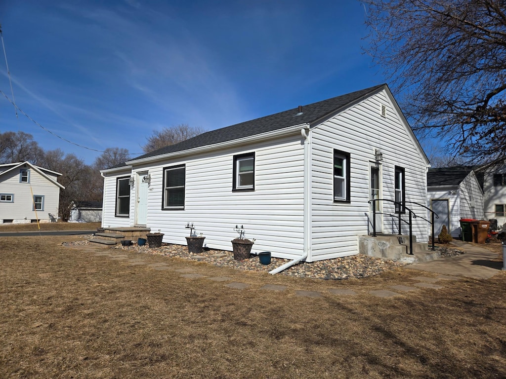 back of house with a yard and a shingled roof