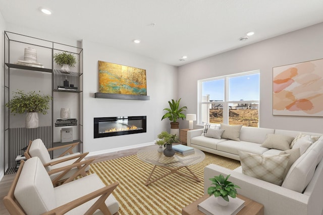 living room with recessed lighting, baseboards, wood finished floors, and a glass covered fireplace