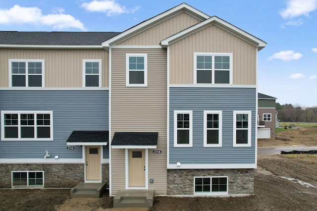 view of front of property with a shingled roof and stone siding