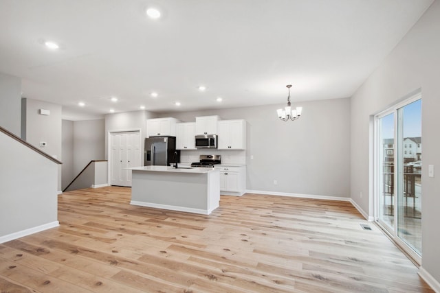 kitchen with white cabinetry, a chandelier, a sink, light wood finished floors, and appliances with stainless steel finishes
