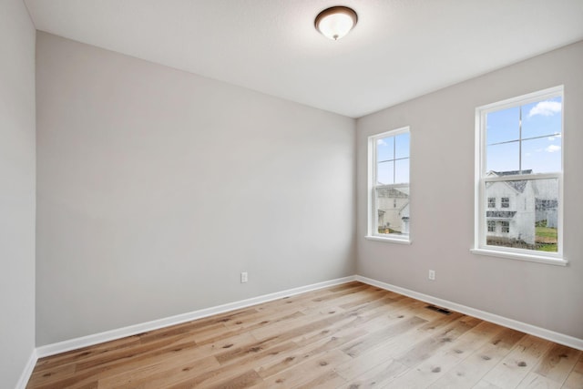 spare room featuring baseboards, light wood finished floors, and visible vents
